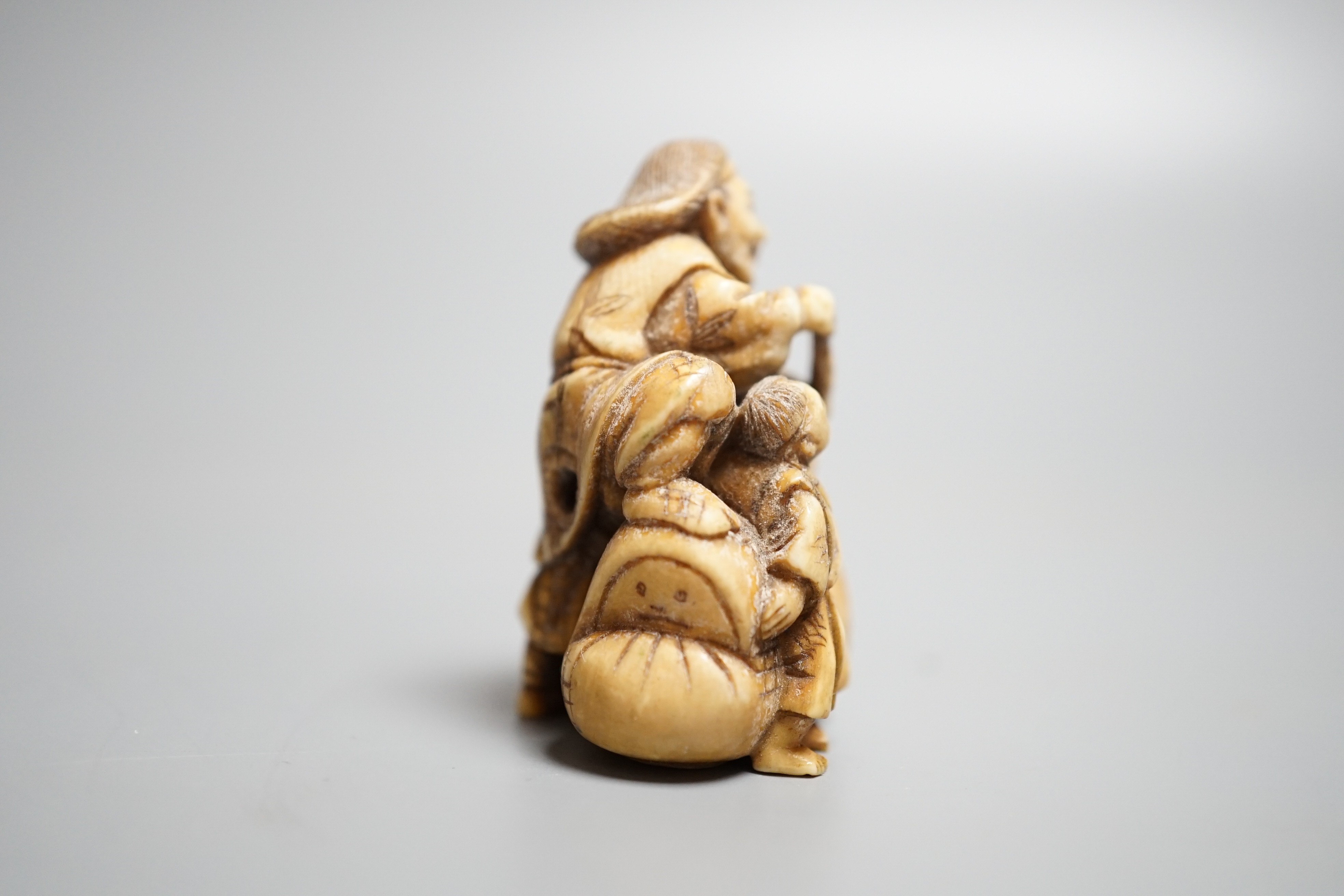 A Japanese ivory netsuke of an artisan and apprentice painting a Daruma doll, early 20th century,height 4cm